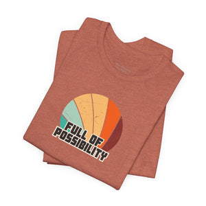 Folded brown t-shirt with 'Full of Possibility' graphic on a white background