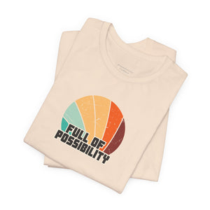 Beige t-shirt with colorful design and 'Full of Possibility' text on a white background