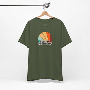 Green t-shirt with colorful graphic and 'Full of Possibility' text on a hanger against a white background
