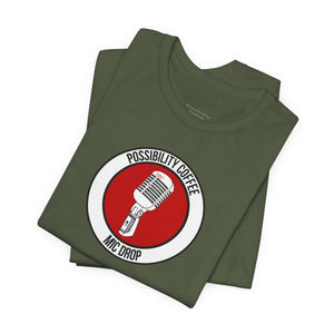 Mic Drop Stack of green t-shirts with a red and white graphic design on a white background