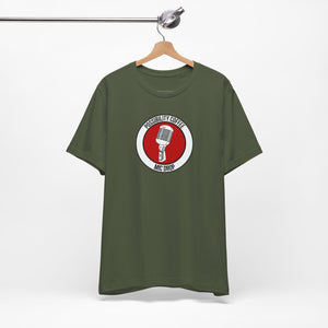 Mic Drop Green t-shirt with a red and white logo on a hanger against a white background