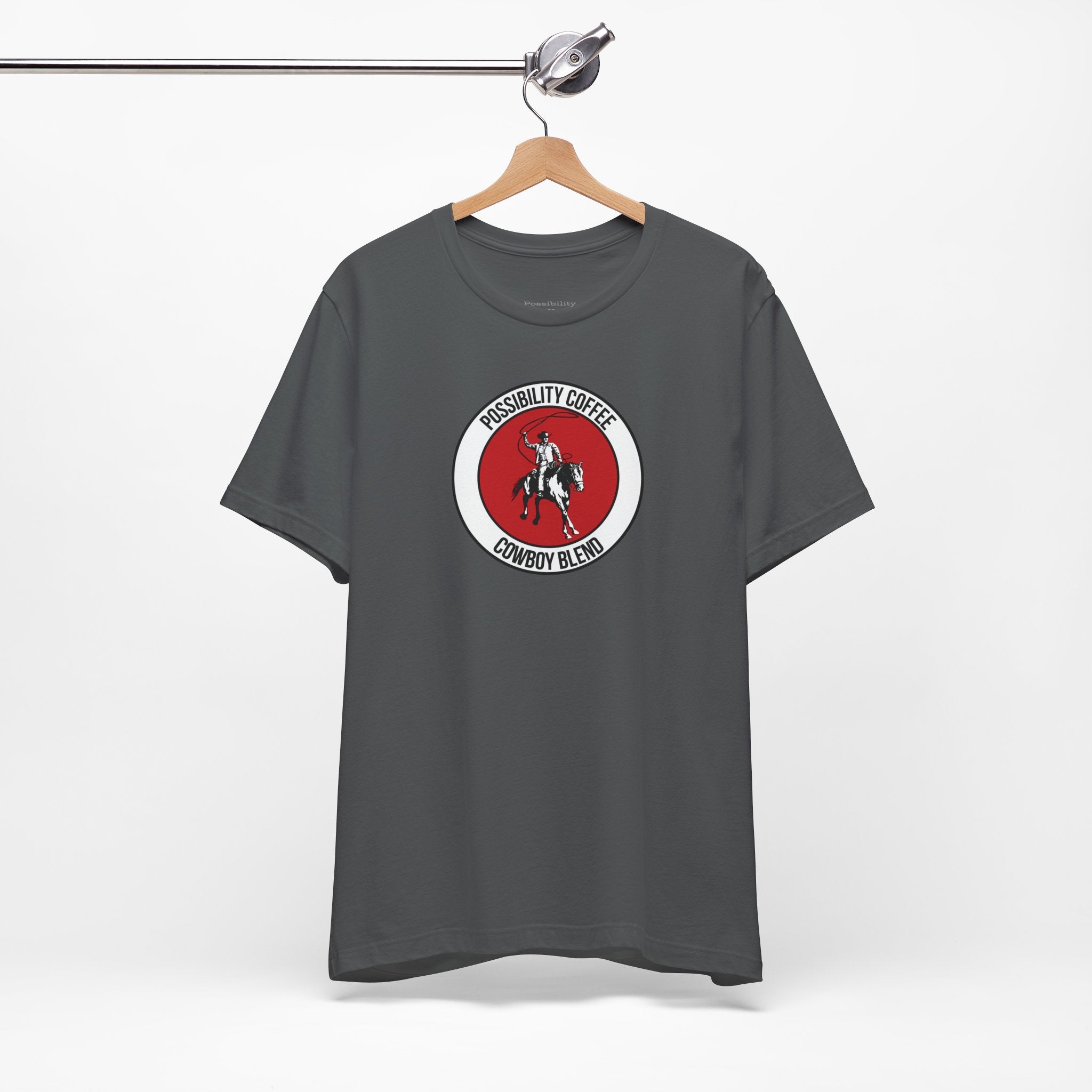 Cowboy Coffee Gray t-shirt with a red and white logo on a hanger against a white background