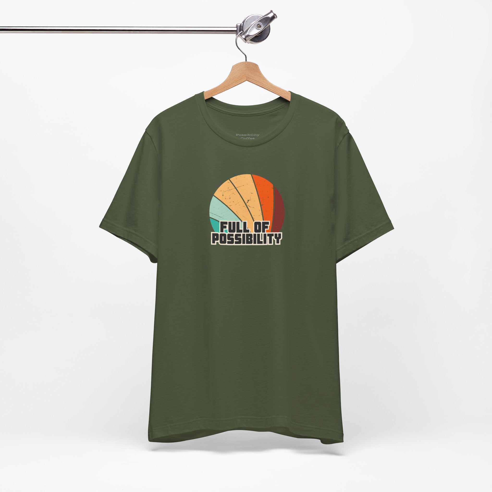 Green t-shirt with colorful graphic and 'Full of Possibility' text on a hanger against a white background