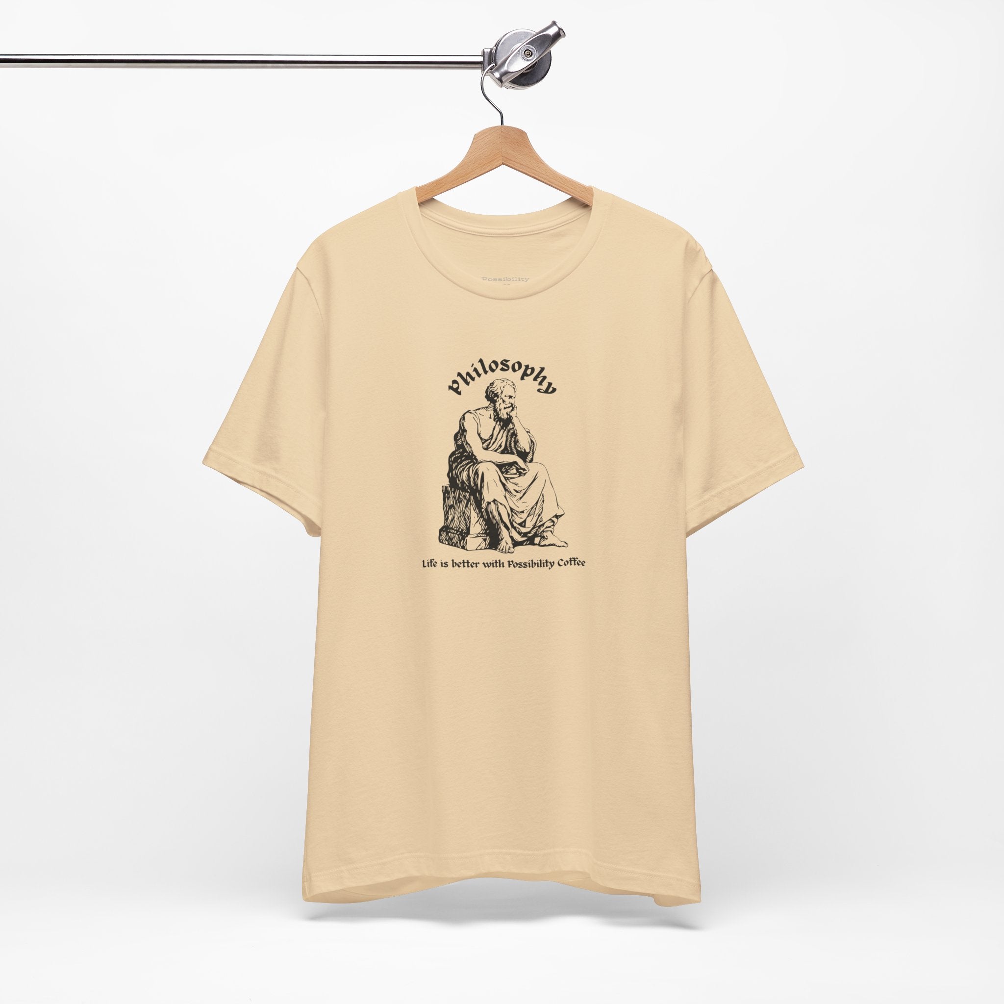 Beige t-shirt with design on a hanger against a white background